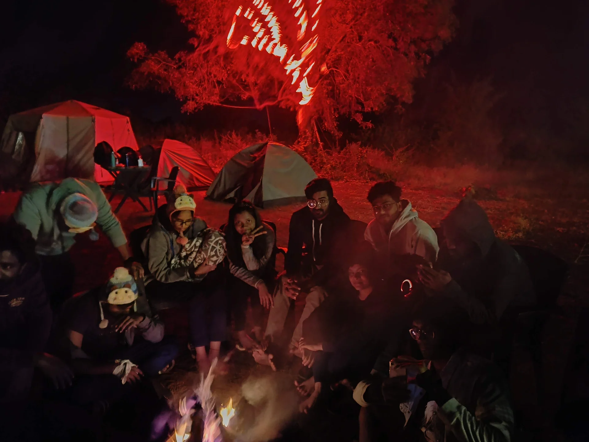 Bonfire with tents and red-lit trees at Ananthagiri