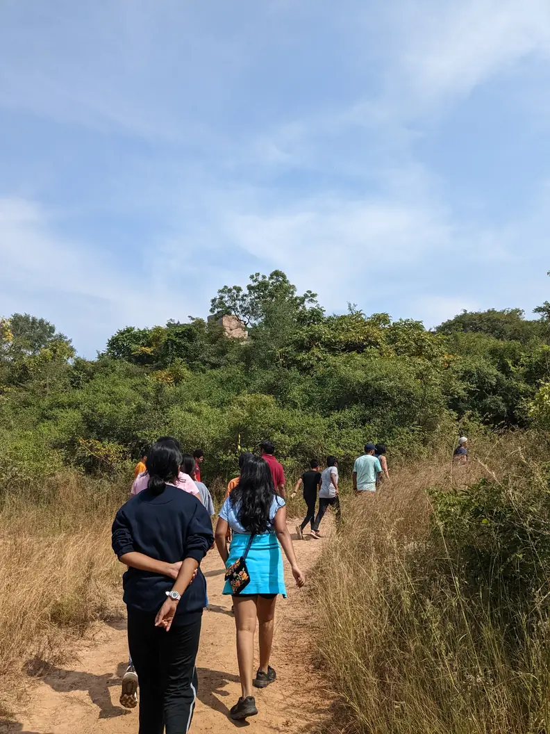 Group trekking toward a rocky hilltop at Pandavulla Gutta